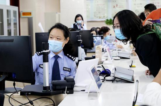 2020年10月14日,原籍浙江湖州的王奇丽(右)在上海市徐汇漕河泾社区事件受理办事中间公安综合窗口,仅用了3分钟就完成了户口迁徙落户手续,成为享受上海市公安局会同浙江省公安厅配合推出的沪浙“跨省市户口网上迁徙”便民步伐的第一人。新华社记者 方喆 摄