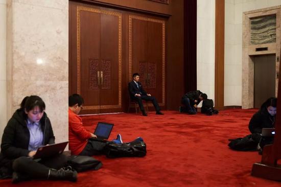 记者们在会议间歇席地而坐，紧张写稿