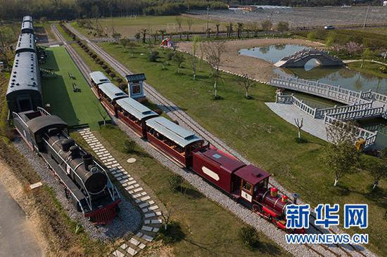 游客乘坐观光小火车从浙江省安吉县鲁家村的休闲驿站边驶过(3月23日无人机拍摄)。新华社记者 黄宗治 摄