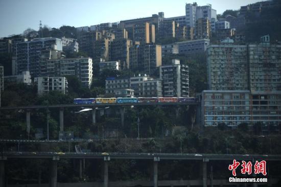资料图：重庆2号线轻轨列车穿过居民楼抵达李子坝站。陈超 摄
