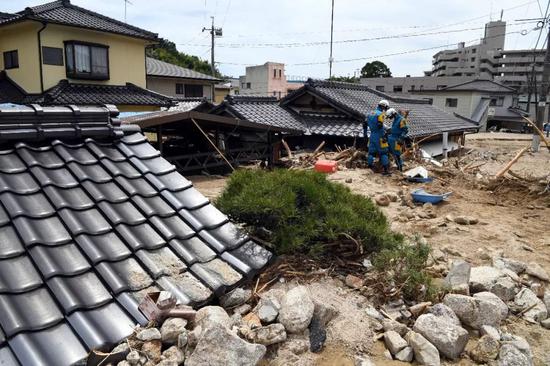 7月11日，在日本广岛吴市天应町地区，警察挖掘被泥石流淹没的民居。新华社记者马平摄