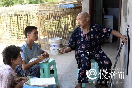 邓林明在院坝的墙上挂上小黑板，给残疾兄妹上数学课。