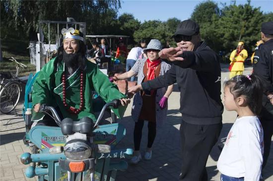 ↑9月22日，提前装扮好的徐有贵（图左）骑着三轮车来到音乐会现场。