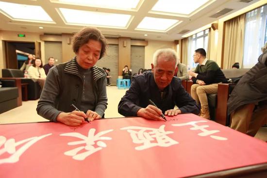 杨柳青木版年画代表性传承人王文达、陈玉华在“年画重回春节”主题采风活动横幅上签名。