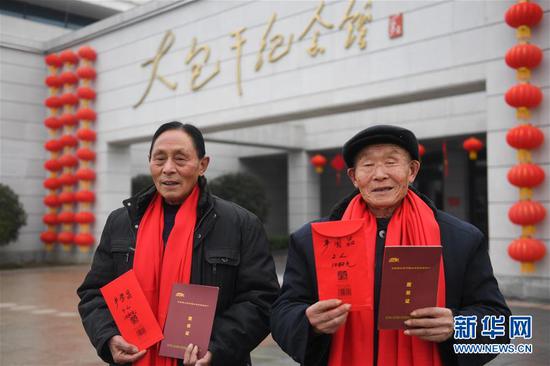 1月28日，在安徽小岗村大包干纪念馆前，“大包干”带头人严学昌（左）和严国品第二次领到集体经济收益股权分红。 新华社记者张端摄