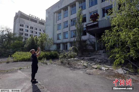 一名游客在切尔诺贝利核电站附近的废弃城市普里皮亚季拍摄一座建筑。