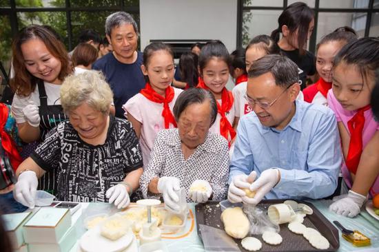 2018年中秋节，幸存者老人夏淑琴（中）与馆长张建军（右）和原副馆长段月萍（左）一起制作月饼（图/侵华日军南京大屠杀遇难同胞纪念馆提供）