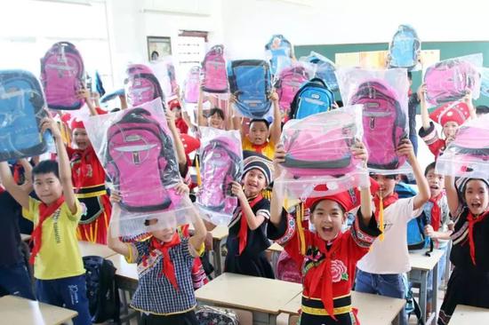  2018年9月21日，广西百色，平果县希望小学的学生展示新书包。（视觉中国图）