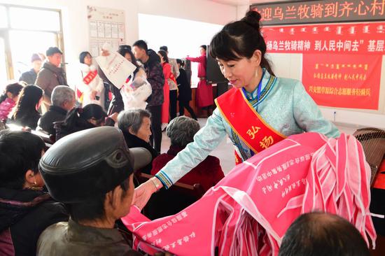 内蒙古兴安盟“草原志愿服务轻骑兵”来到基层开展志愿服务,工作人员向群众发放免费围裙。新华社记者贝赫摄