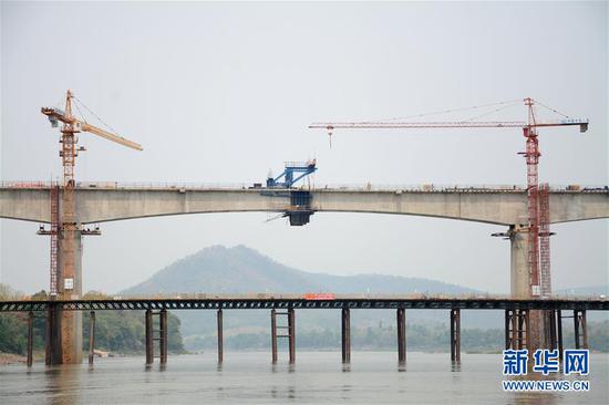 这是2019年5月21日在老挝拍摄的首跨合龙的中老铁路琅勃拉邦湄公河特大桥。中老铁路北起两国边境,南抵万象,是第一个以中方为主投资建设、中老共同运营并与中国铁路网直接连通的境外铁路项目。线路全长414公里,其中桥梁长度近62公里,隧道长度近198公里。中老铁路全线采用中国技术标准、使用中国设备,2016年12月全线开工,计划于2021年12月建成通车。 新华社发(段小平摄)