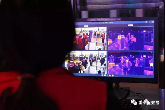 ▲ 1月21日,武汉火车站,工作人员通过仪器对旅客体温进行检测。摄影/新京报记者 游天燚