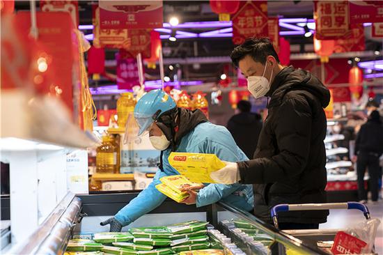 1月27日,武汉市民和外卖代购小哥在一家盒马鲜生店内选购商品。新华社记者 熊琦 摄