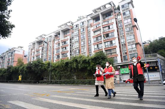 2月1日,重庆市北碚区北温泉街道作孚路社区党委书记王永琴(中)与同事在社区内走访排查。新华社记者 唐奕 摄