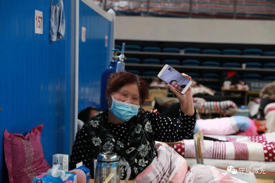 2月21日,武汉市洪山体育馆方舱医院A区内,一名患者正在与家族视频通话,给家族看方舱医院里面的环境。中青报·中青网见习记者 鲁冲/摄