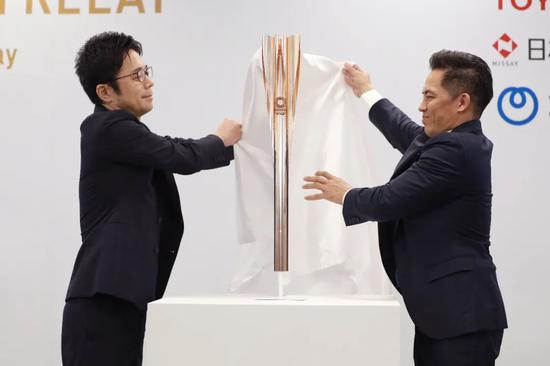 2019年3月20日,東京奧運會聖火傳遞大使、柔道名將野村忠宏(右)與火炬設計師吉岡德仁在發佈會上爲火炬揭幕