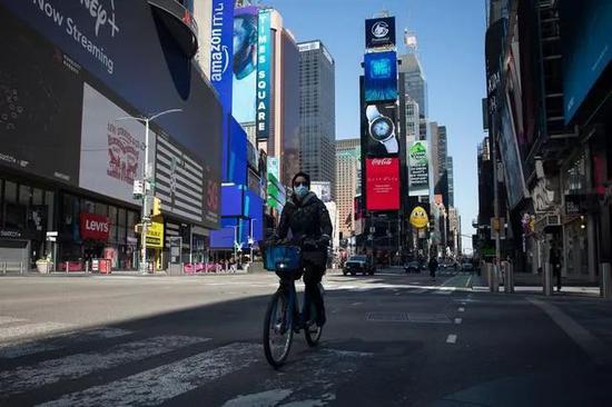 26日，在美国纽约，一名戴口罩的骑车人经过曼哈顿时报广场。图源：新华社