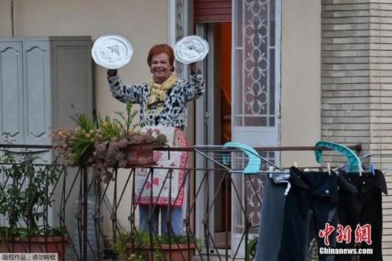 ▲意大利罗马，一位居民用锅盖敲钹，参加名为“从窗户往外看，我的罗马”的音乐快闪活动。