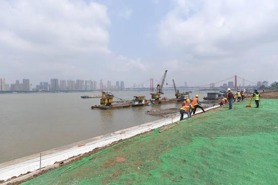 武昌区八铺街防洪及情况综合整治工程位于武昌区鹦鹉洲大桥和杨泗港大桥之间,全长3.8公里,包罗滩地及岸坡整治、闸口革新、绿化景观革新等,现场复工工人们正在加紧施工。长江日报记者周超 摄