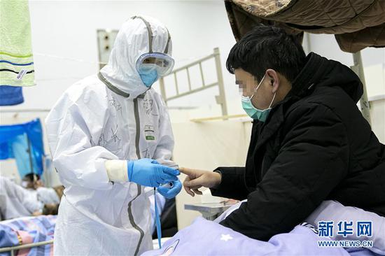 2月10日，在武汉客厅方舱医院，来自福建医疗队1990年出生的薛文新（左）为患者检测血氧含量。新华社记者 熊琦 摄