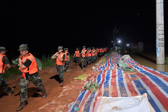 2020年7月11日，武警江西总队机动支队官兵在鄱阳县江家岭村昌江圩抗洪一线搬运沙袋。 本文照片均由武警江西总队战士 许书灿 摄