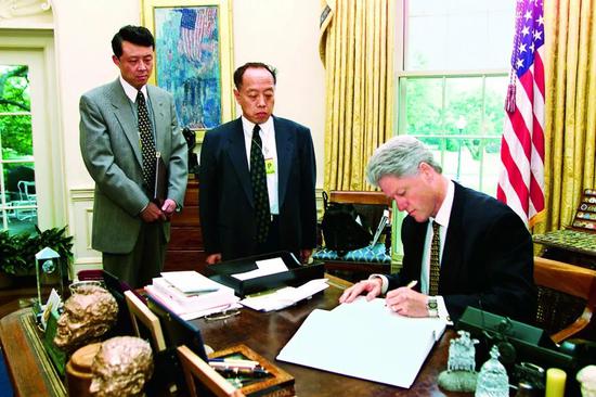 ·1999年,时任驻美大使李肇星(中)和时任驻美公使刘晓明(左)前往白宫交涉。时任美国总统克林顿就美国轰炸中国驻南联盟大使馆事件,写下哀悼遇难者的话。