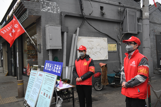 2020年2月27日,自愿者张开国(左)和儿子张洪赫在北京市东城区清闲门街道花圃社区车辇店胡同口的疫情防控值班点值守。新华社记者 鞠焕宗 摄
