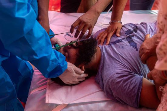 5月6日，一名新冠患者在印度加济阿巴德一处路边帐篷吸氧。新华社 图