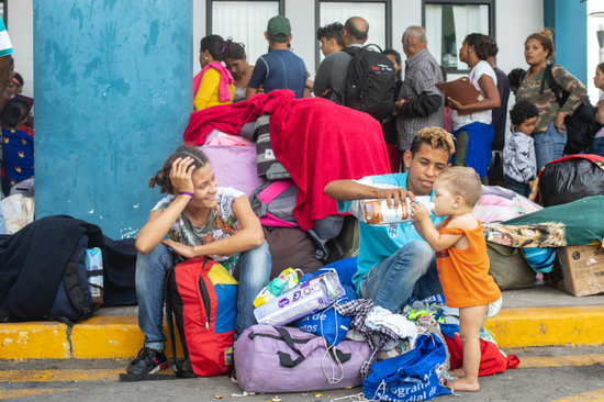 一个委内瑞拉家庭在厄瓜多尔、秘鲁边境稍事休息，准备排队获取相关文件合法入境秘鲁。© UNHCR/Hélène Caux