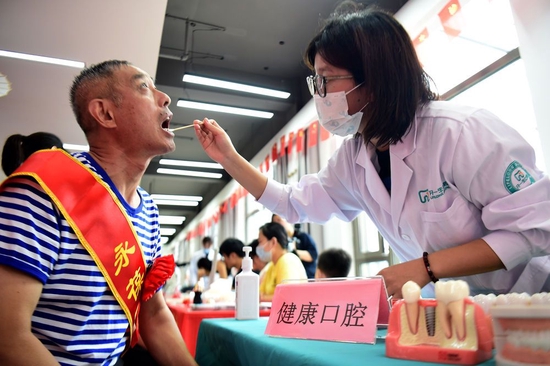 安徽省合肥市蜀山区洪岗社区志愿者为市民检查口腔(2022年7月29日摄)。新华社记者 黄博涵 摄