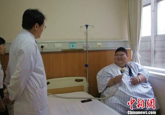 19岁的山东莱芜小伙王浩楠凭借688斤的“重量”走红网络，目前已入院治疗，渴望减到200斤。图为王浩楠与他的主治医生正在交流治疗方法。　赵晓　摄