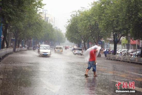 一名男子用塑料薄膜挡雨,在雨中奔跑。 朱柳融 摄
