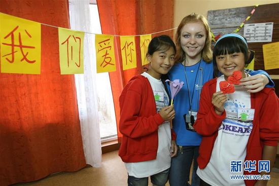  2008年7月21日，在“海洋”全俄儿童中心，两个中国小姑娘和她们的折纸课老师合影留念。图片来源：新华社