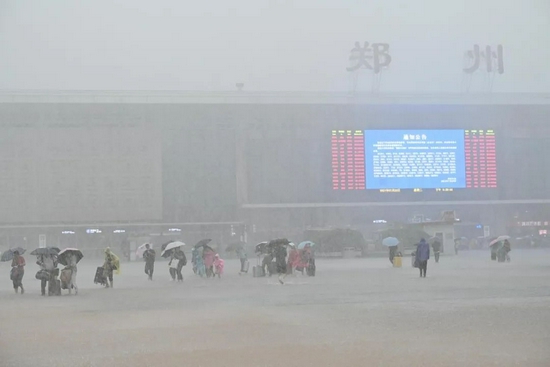 2021年7月20日,郑州遭遇持续强降雨。图为郑州火车站,旅客涉水前行。