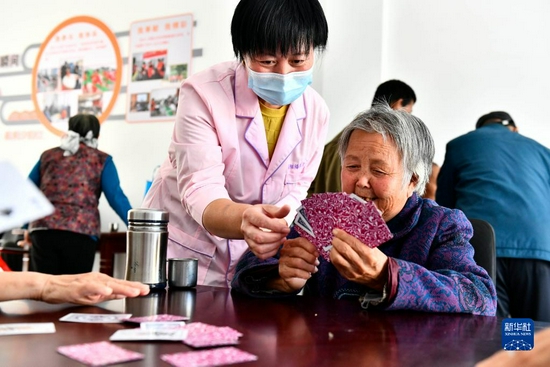 在山东省东营市垦利区杨庙社区养老服务中心，工作人员陪老人打扑克（10月18日摄）。新华社记者 郭绪雷 摄