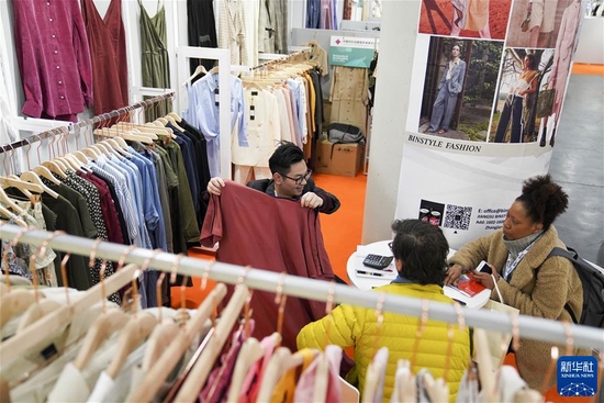 在美国纽约举行的第二十一届中国纺织品服装贸易展览会（纽约）春季展上，江苏一家企业的工作人员（左）为访客介绍产品（2020年1月21日摄）。 新华社记者 王迎 摄