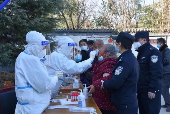 李玉斌和老伴在民警的搀扶下做核酸检测。（照片由受访者提供）