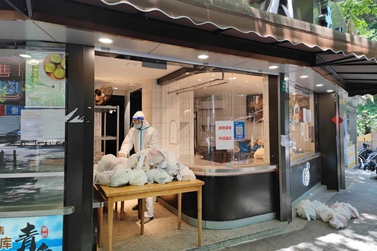 5月2日，疫情防控下的上海街头，一家熟食店店员整理线上销售的食品（图|人民视觉）