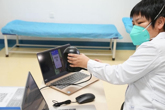  5月22日，在北京市丰台区卢沟桥社区卫生服务中心，医务工作者通过视频连线的方式为预约上门治疗的患者扫描电子医保卡。（新华社记者鞠焕宗 摄）
