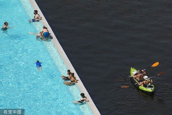 当地时间2022年7月19日，德国柏林，人们在施普雷河上划桨，经过贝德西夫游泳馆。视觉中国 资料图