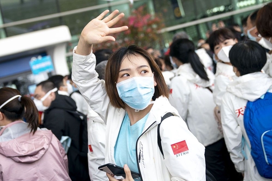 2020年3月17日,在武汉天河机场,完成援鄂任务后随队撤离的天津国家紧急医学救援队队员张硕向送行的人们挥手告别。新华社记者 熊琦 摄