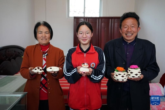 在山西省霍州市师庄乡冯南垣村,师菁悦(中)和爷爷师红兵(右)、奶奶朱海丹(左)在展示年馍(2022年5月14日摄)。新华社记者 詹彦 摄