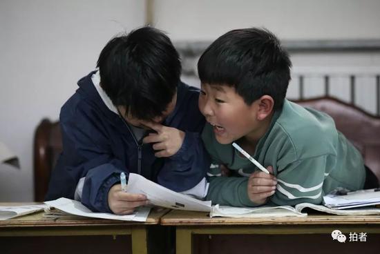 4月4日，河北涞水西官庄村，“小课桌”上，两位小朋友正在商量习题。新京报记者尹亚飞 摄