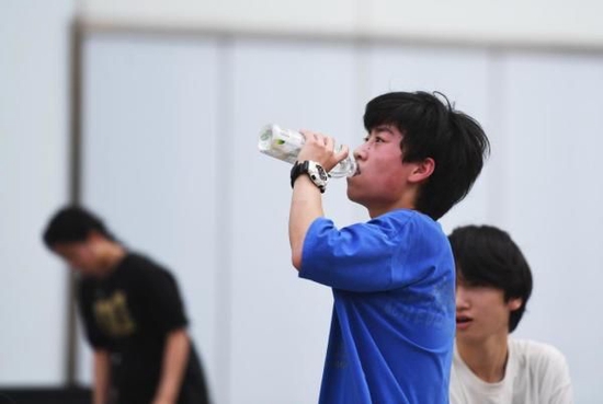 6月21日,在河南省郑州市金水区花园路,男孩在运动后补水。新华社记者 张浩然 摄