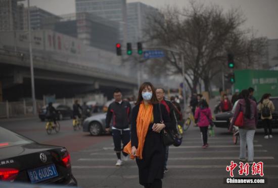 资料图：北京市民在雾霾中出行。 中新社记者 刘关关 摄