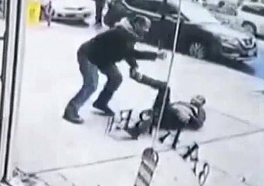 女子倒在人行道上试图用脚来反抗丈夫的攻击