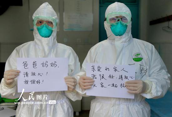 2020年2月6日,江苏省连云港市市立东方医院医生王彩(右)和护士许思佳在发热门诊下夜班后,给各自的家人报平安。王健民/人民图片