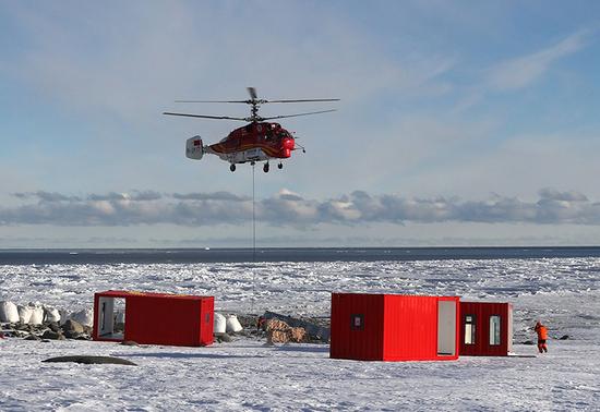 船载“雪鹰12”Ka-32直升机将物资吊运至恩克斯堡岛新建站区(2017年12月9日摄)。新华社记者 白国龙 摄