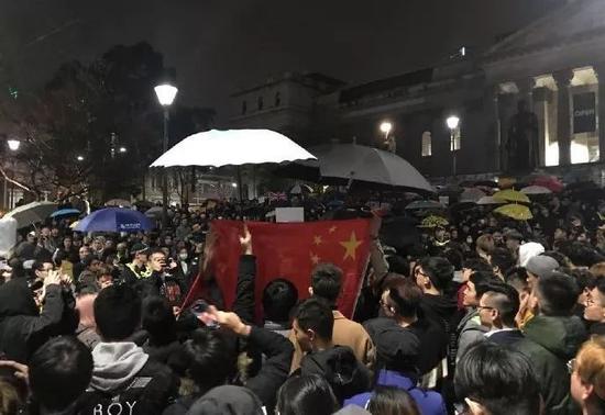 16日晚,澳大利亚墨尔本州立图书馆前,留学生们“雨中护旗”