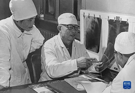 1980年1月16日，辛育龄（中）在内蒙古结核病院与胸外科医师讨论病例（翻拍照片）。新华社发