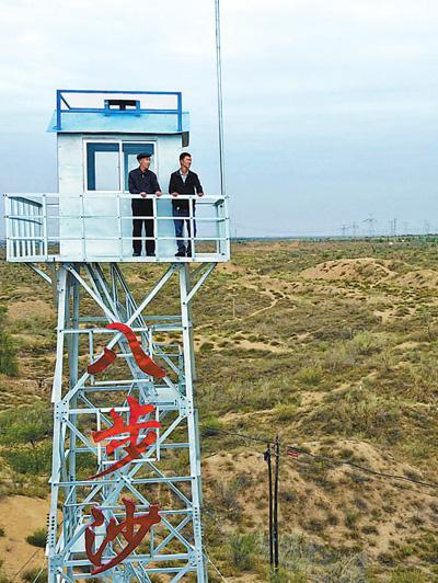 第二代治沙人郭万刚（左）和第三代治沙人郭玺在林场瞭望塔查看防沙治沙情况。新华社记者 范培珅摄